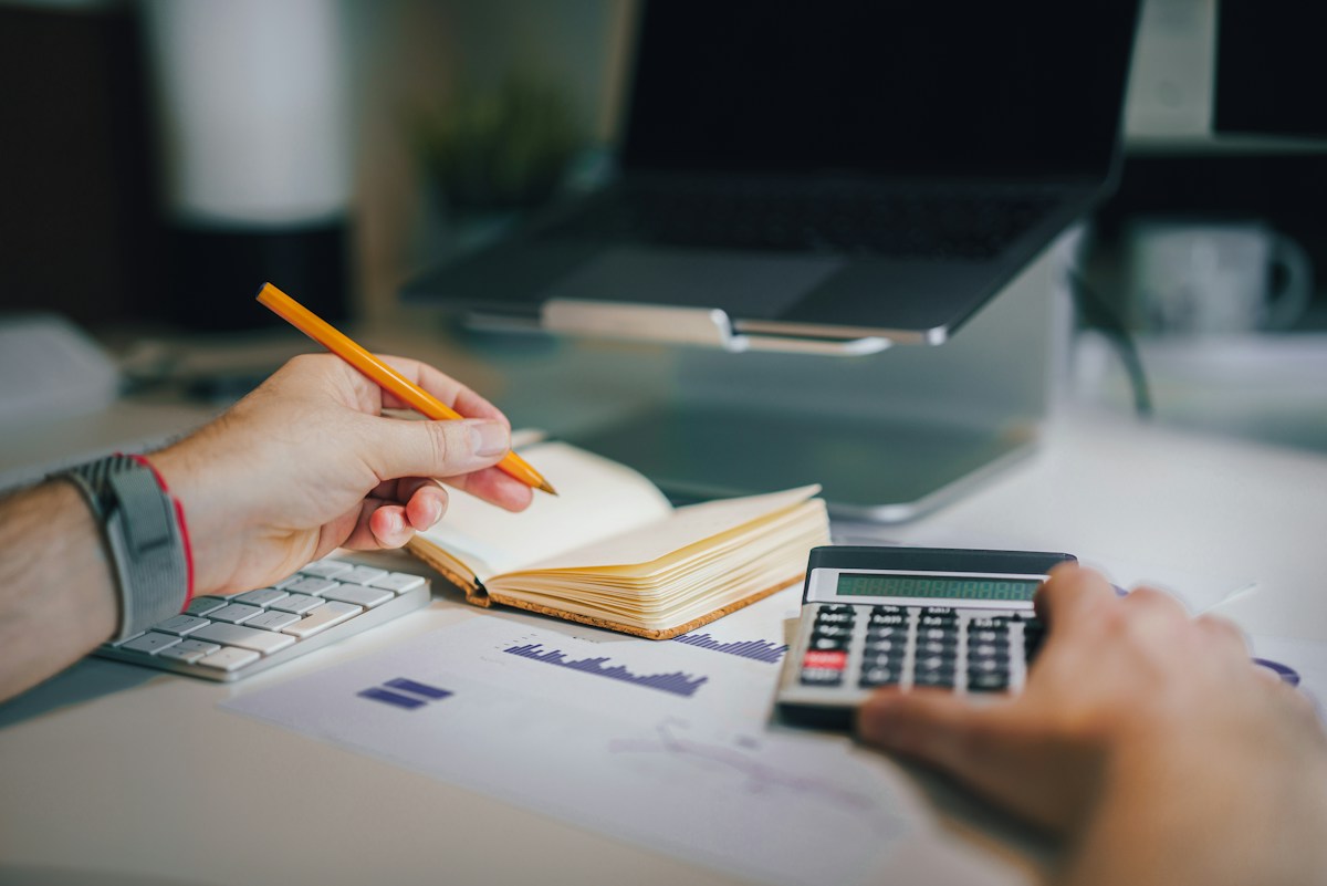 An accounting professional working with a calculator and laptop