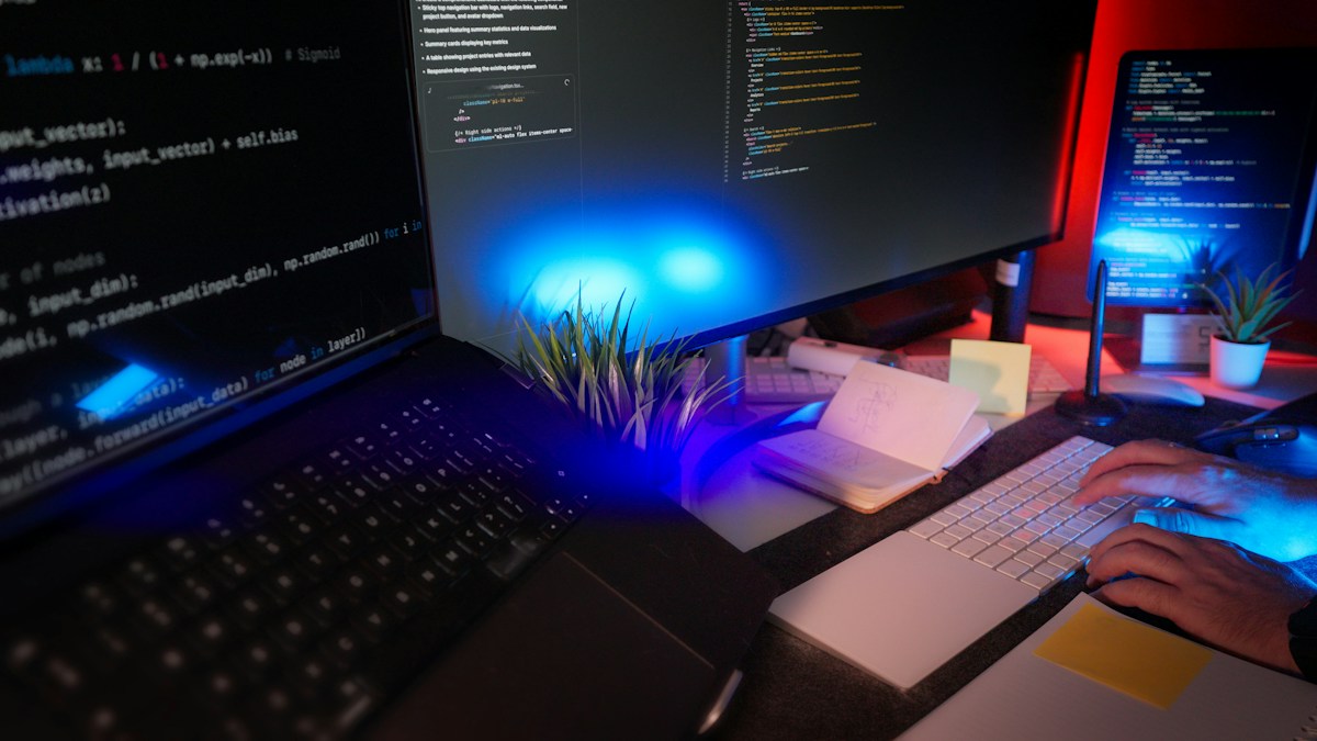 A software developer working across multiple monitors